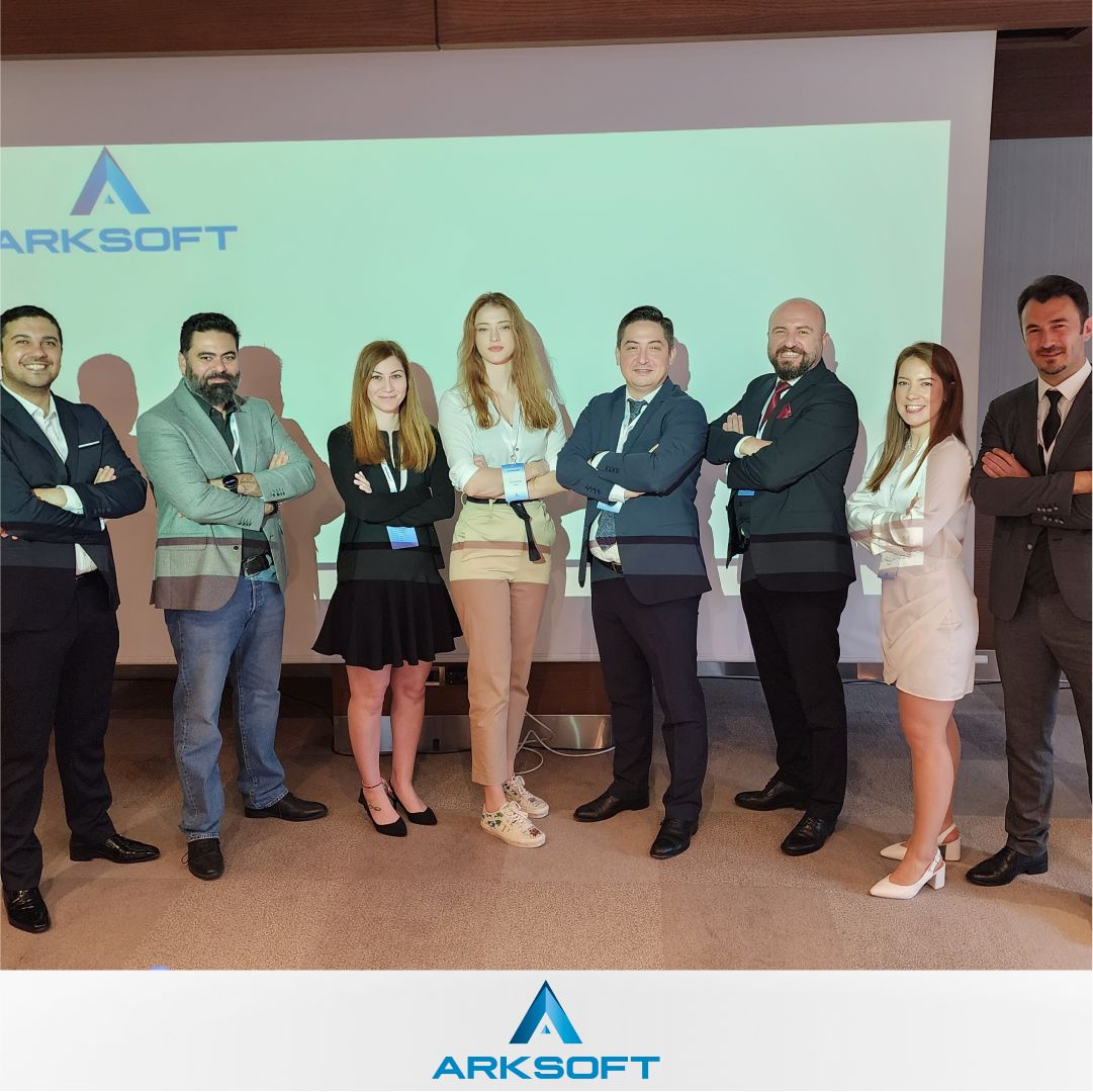 ARKSOFT team hosting a meeting in Istanbul, standing together in business attire with the company logo in the background